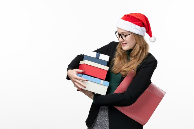 Vista frontal joven mujer sosteniendo regalos navideños en la pared blanca regalo de año nuevo navidad