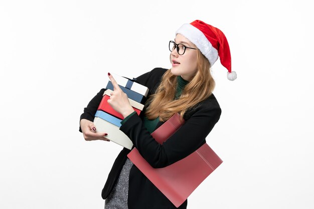 Vista frontal joven mujer sosteniendo regalos navideños en pared blanca regalo año nuevo