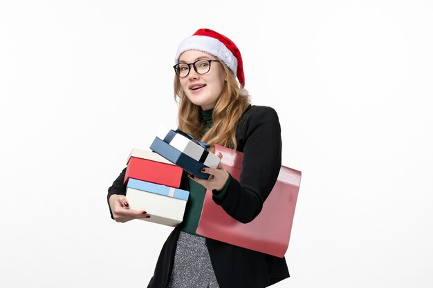 Vista frontal joven mujer sosteniendo regalos navideños en piso blanco libro de regalo año nuevo