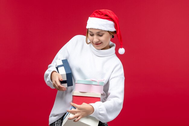 Foto gratuita vista frontal joven mujer sosteniendo regalos navideños sobre fondo rojo.