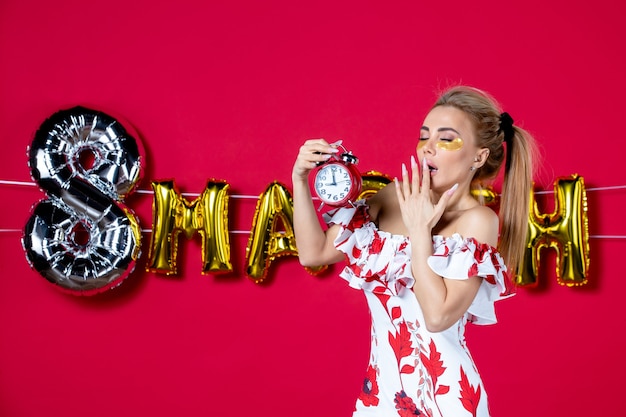 Foto gratuita vista frontal joven mujer sosteniendo relojes en rojo decorado