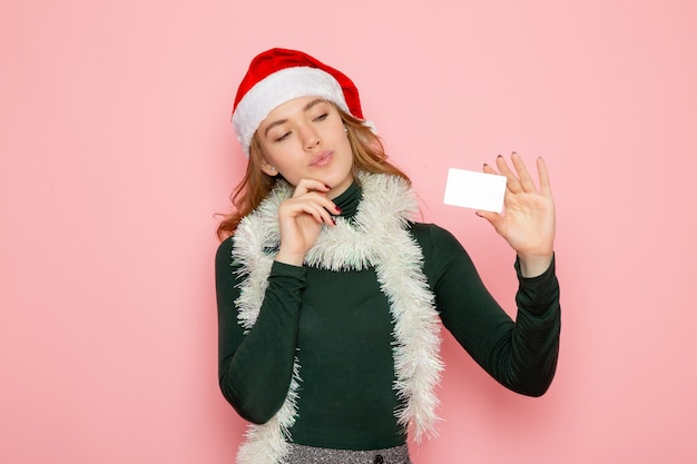 Vista frontal joven mujer sosteniendo tarjeta bancaria en la pared rosa color modelo vacaciones año nuevo emoción