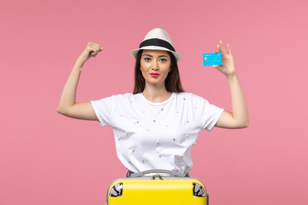 Vista frontal joven mujer sosteniendo tarjeta bancaria en la pared rosa mujer viaje verano emoción