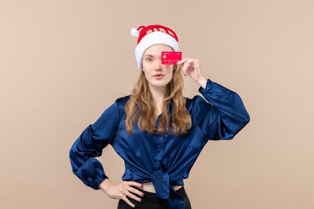 Vista frontal joven mujer sosteniendo tarjeta bancaria roja sobre fondo rosa vacaciones Navidad dinero foto año nuevo emoción