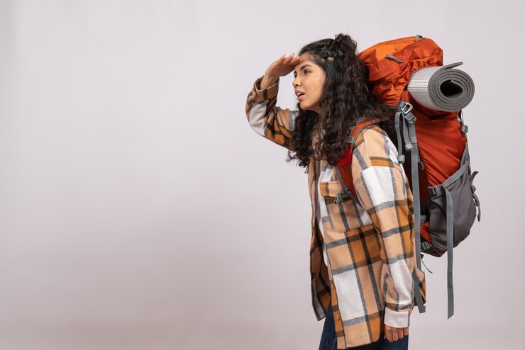 Vista frontal joven mujer yendo de excursión con mochila mirando a distancia sobre fondo blanco campus turístico vacaciones montaña viaje bosque aire