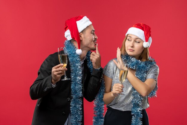 Vista frontal de la joven pareja celebrando el año nuevo en el escritorio rojo amor color de navidad