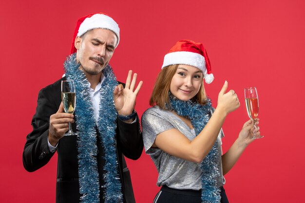 Foto gratuita vista frontal joven pareja celebrando el año nuevo en la pared roja amor bebidas de fiesta de navidad