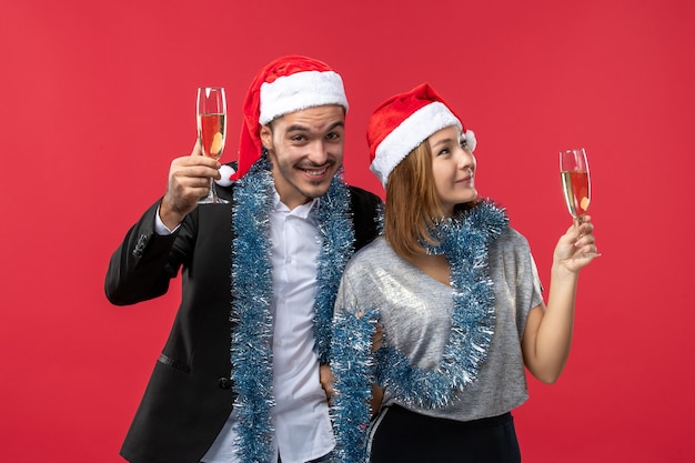 Foto gratuita vista frontal joven pareja celebrando el año nuevo en la pared roja amor fiesta navidad