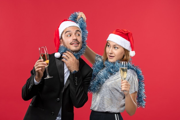 Vista frontal joven pareja celebrando el año nuevo en la pared roja amor fiesta de navidad