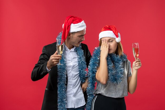 Vista frontal joven pareja celebrando el año nuevo en la pared roja amor fiesta navidad