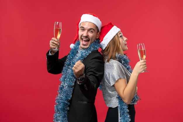 Vista frontal joven pareja celebrando el año nuevo en la pared roja amor navidad