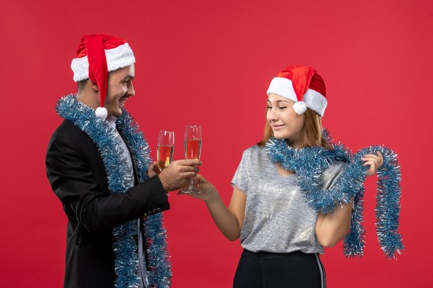 Vista frontal joven pareja celebrando el año nuevo en la pared roja color amor navidad