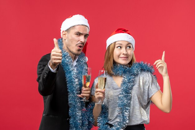 Vista frontal joven pareja celebrando el año nuevo en la pared roja fiesta de amor de navidad