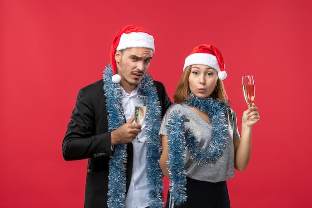 Vista frontal joven pareja celebrando el año nuevo en la pared roja fiesta amor de navidad