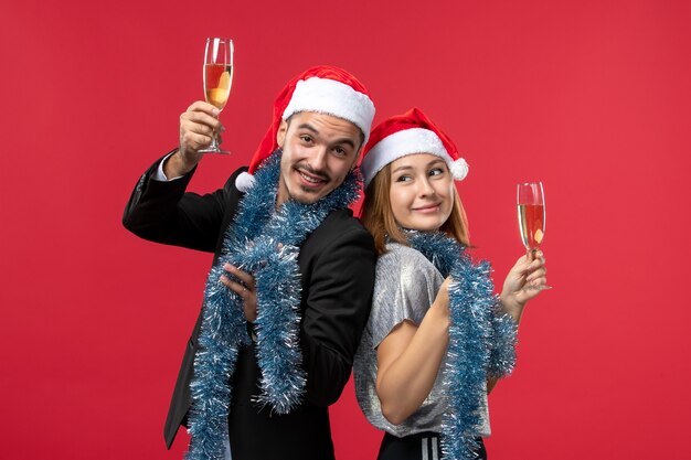 Vista frontal joven pareja celebrando el año nuevo en la pared roja fiesta amor navidad