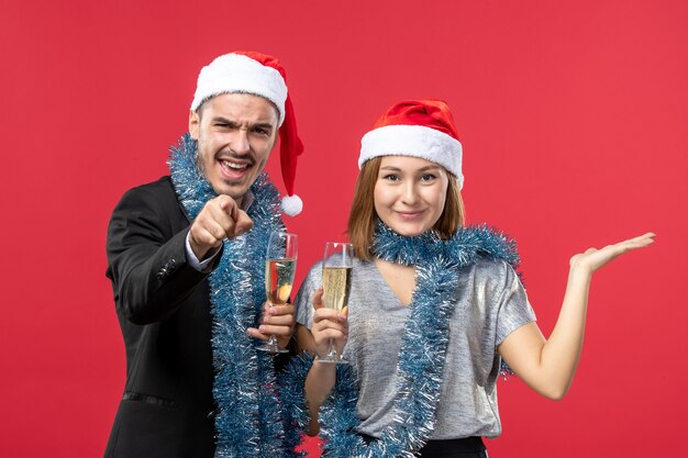 Vista frontal joven pareja celebrando el año nuevo en la pared roja fiesta de amor de navidad