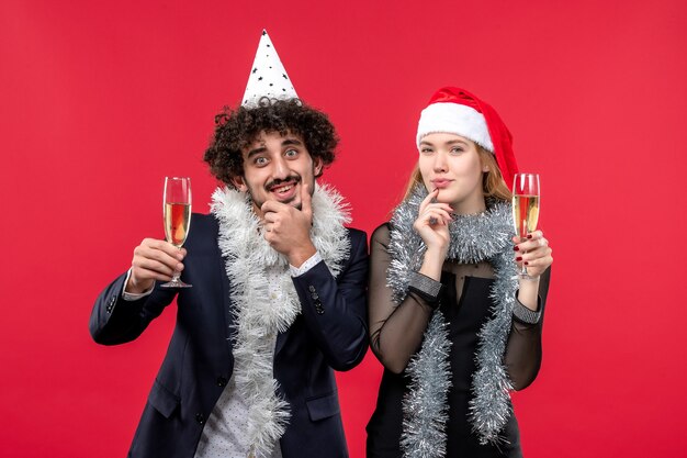 Vista frontal joven pareja celebrando el año nuevo en la pared roja fiesta de amor de navidad