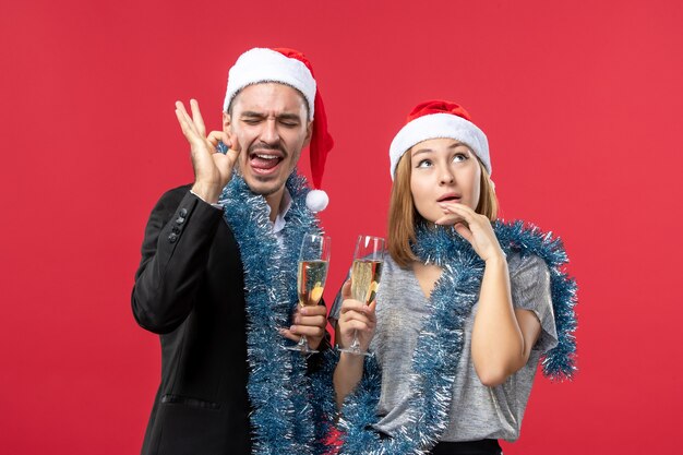 Vista frontal joven pareja celebrando el año nuevo en la pared roja fiesta amor de navidad