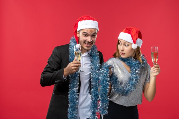 Vista frontal joven pareja celebrando el año nuevo en la pared roja fiesta amor de navidad