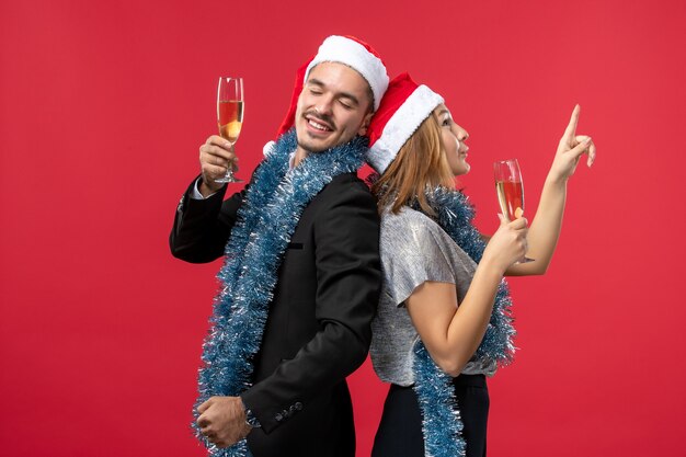 Vista frontal joven pareja celebrando el año nuevo en la pared roja fiesta amor navidad