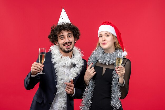 Vista frontal joven pareja celebrando el año nuevo en la pared roja fiesta de amor de navidad