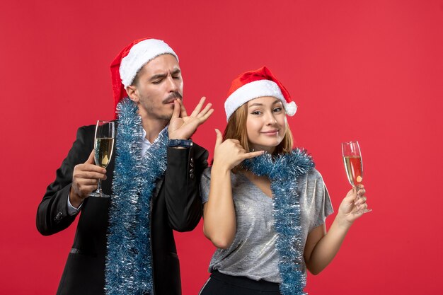 Vista frontal joven pareja celebrando el año nuevo en la pared roja fiesta de navidad beber amor