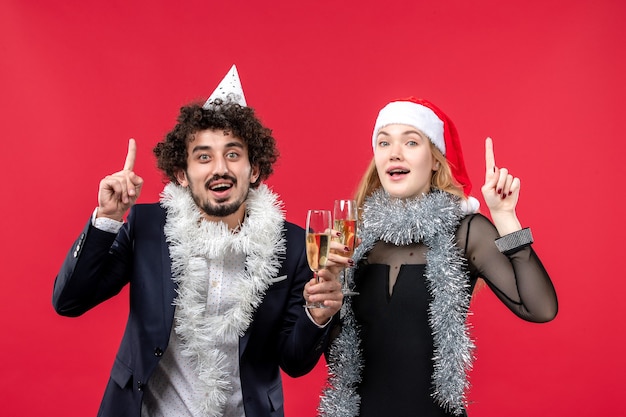 Vista frontal joven pareja celebrando el año nuevo en la pared roja foto amor de navidad