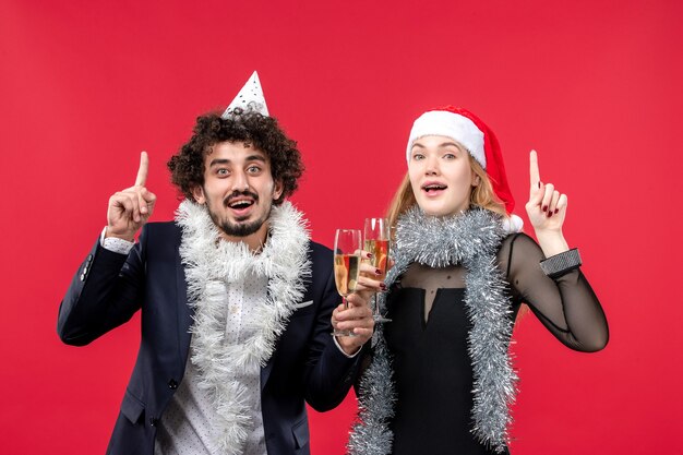 Vista frontal joven pareja celebrando el año nuevo en la pared roja foto amor de navidad