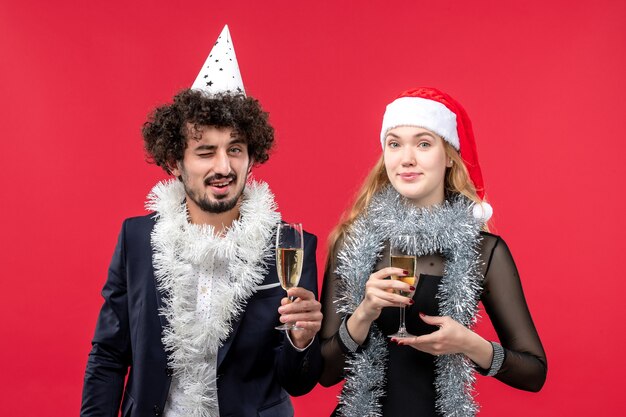 Vista frontal joven pareja celebrando el año nuevo en la pared roja foto color de amor de navidad