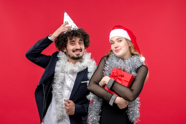 Vista frontal joven pareja celebrando el año nuevo en la pared roja navidad amor vacaciones