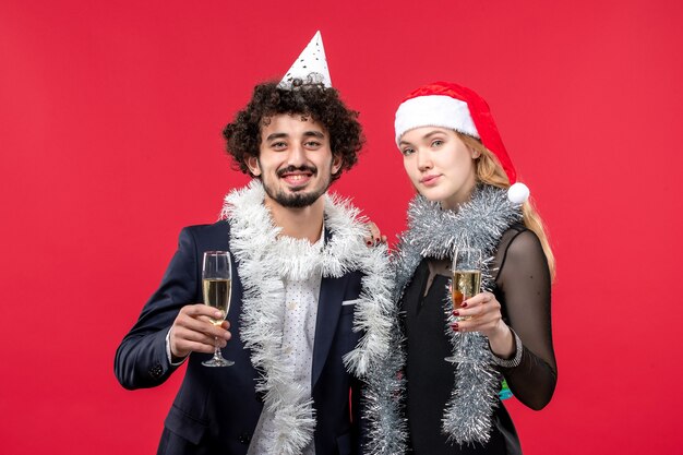 Vista frontal joven pareja celebrando el año nuevo en la pared roja vacaciones amor de navidad