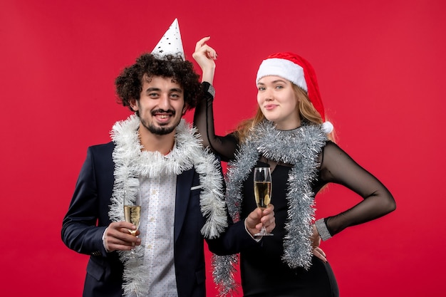 Vista frontal joven pareja celebrando el año nuevo en la pared roja vacaciones amor de navidad