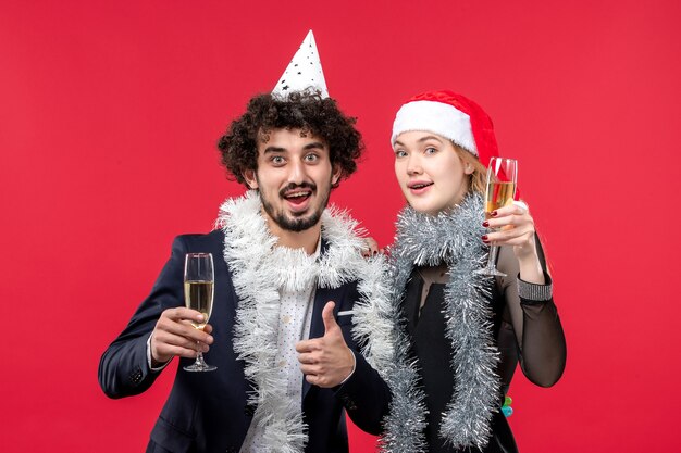 Vista frontal joven pareja celebrando el año nuevo en la pared roja vacaciones amor de navidad