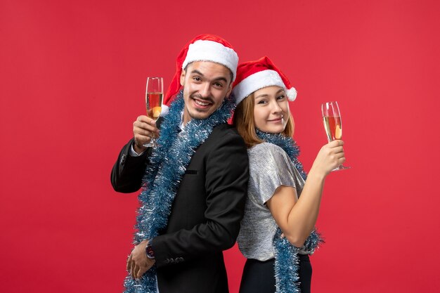 Vista frontal de la joven pareja celebrando el año nuevo en la pared roja.