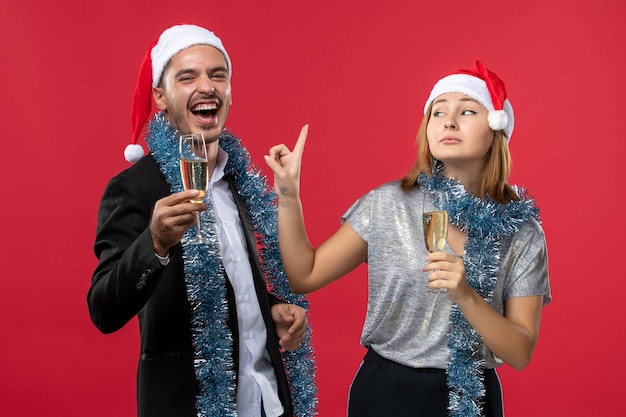 Vista frontal de la joven pareja celebrando el año nuevo en el piso rojo amor color de navidad