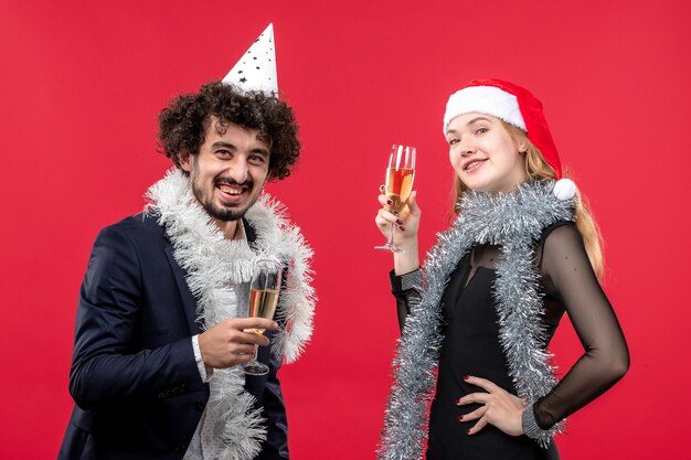 Vista frontal joven pareja feliz celebrando el año nuevo en el amor de navidad de vacaciones de piso rojo