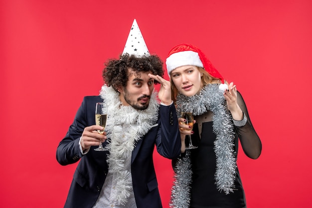 Vista frontal joven pareja feliz celebrando el año nuevo en la pared roja foto amor de navidad