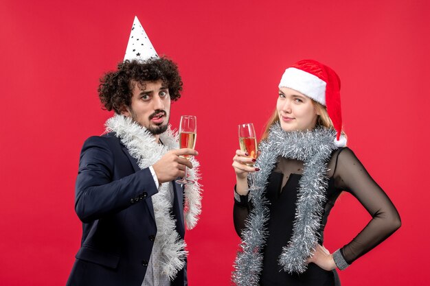 Vista frontal joven pareja feliz celebrando el año nuevo en la pared roja vacaciones amor de navidad