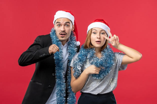 Vista frontal joven pareja feliz en el estado de ánimo de año nuevo en el amor de navidad de color rojo de la pared