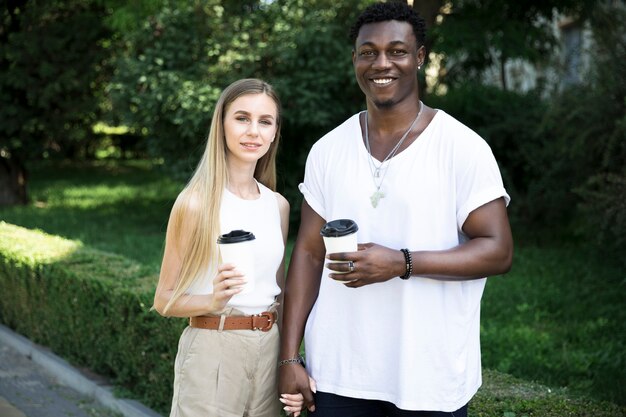 Vista frontal joven pareja multicultural tomados de la mano