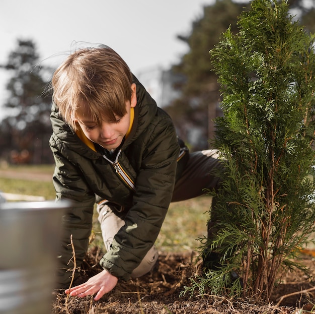 Foto gratuita vista frontal del joven plantar un árbol al aire libre