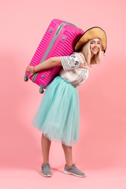 Foto gratuita vista frontal joven preparándose para las vacaciones de verano llevando una bolsa de color rosa sobre un fondo rosa viaje viaje vacaciones hidroavión color de descanso