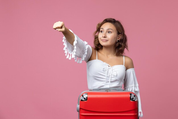 Foto gratuita vista frontal de la joven preparándose para el viaje con bolsa roja en la pared rosa