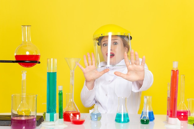 Foto gratuita vista frontal joven químico femenino en traje blanco con soluciones ed trabajando con ellos con casco en la ciencia química espacial amarilla