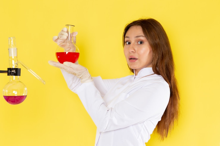 Foto gratuito vista frontal de joven químico femenino en traje blanco con soluciones químicas trabajando con ellos