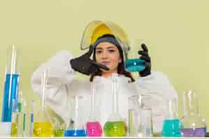 Foto gratuita vista frontal joven químico femenino en traje de protección especial que trabaja con soluciones en la ciencia del trabajo de química de laboratorio químico de pared verde
