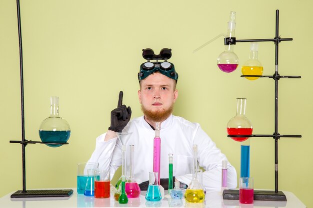 Vista frontal joven químico pensando en un nuevo examen químico en un laboratorio