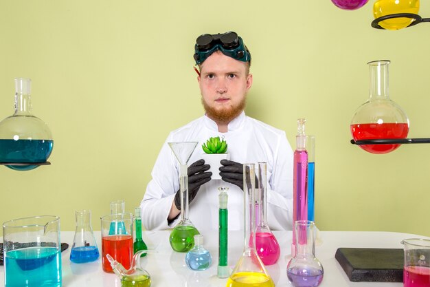 Vista frontal joven químico sosteniendo su planta fresca en un laboratorio