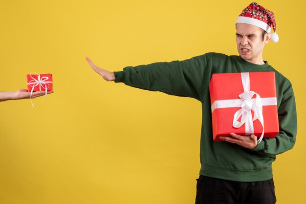 Vista frontal joven rechazando el regalo en mano femenina en amarillo