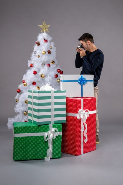 Vista frontal joven con regalos de Navidad en el gris